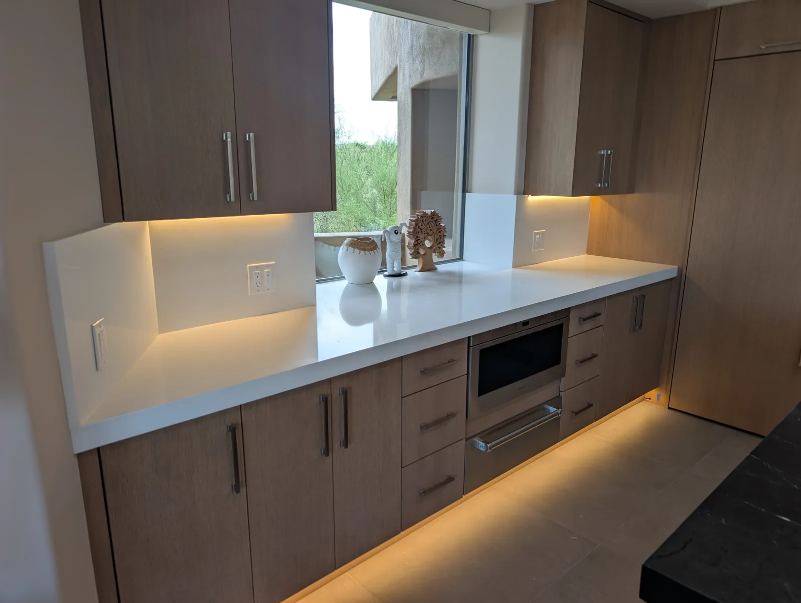 White stone perimeter counter and backsplash by a kitchen window