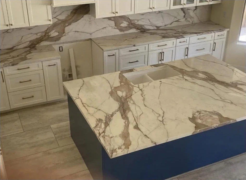Scottsdale residence kitchen with veined stone countertops, a matching backsplash, white cabinetry, and a blue island